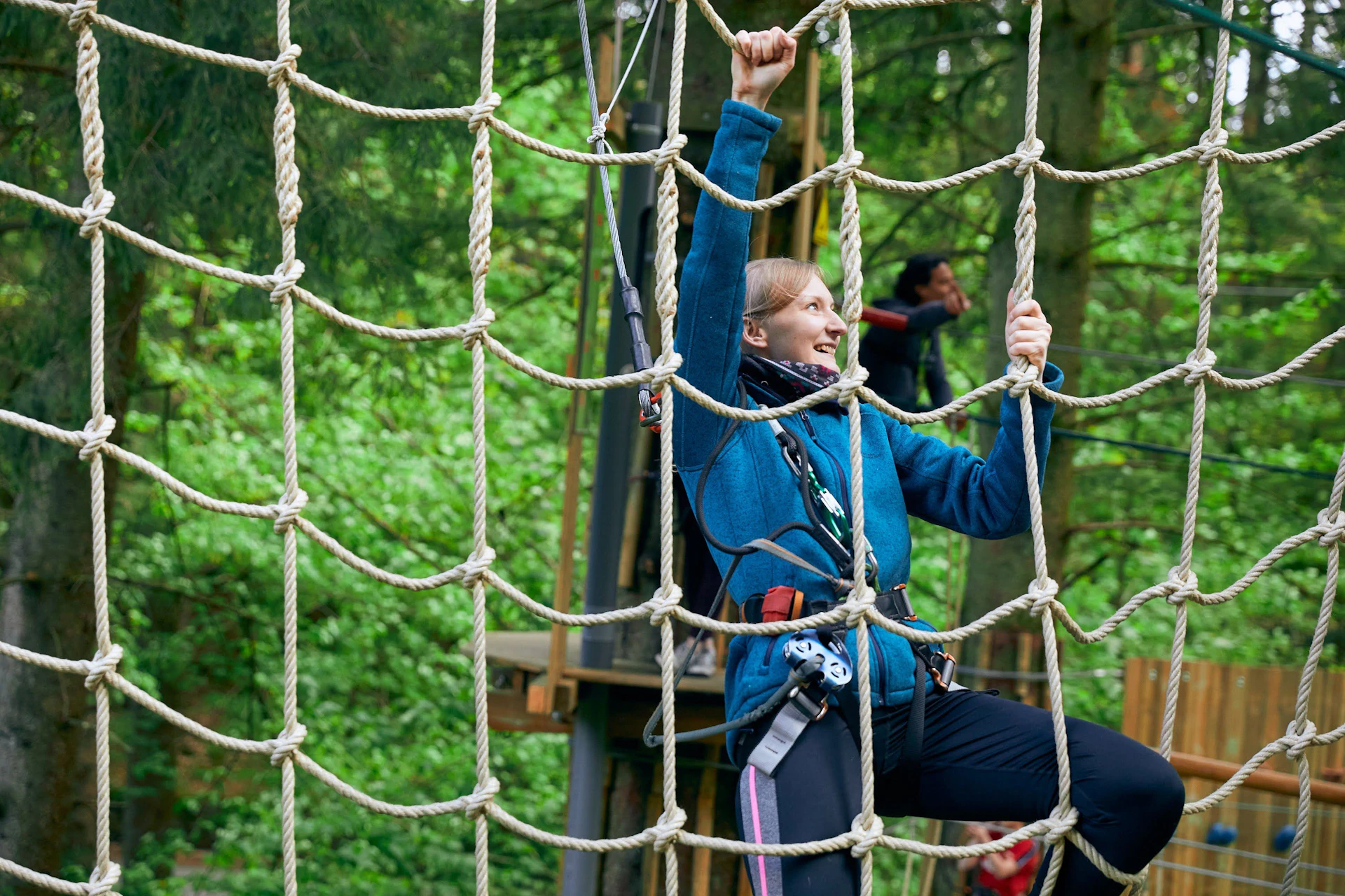 woman climbing through the trees with a harness